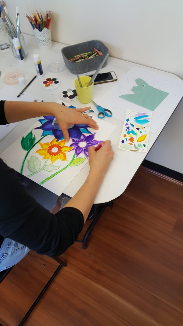 Hands painting rainbow sunflowers